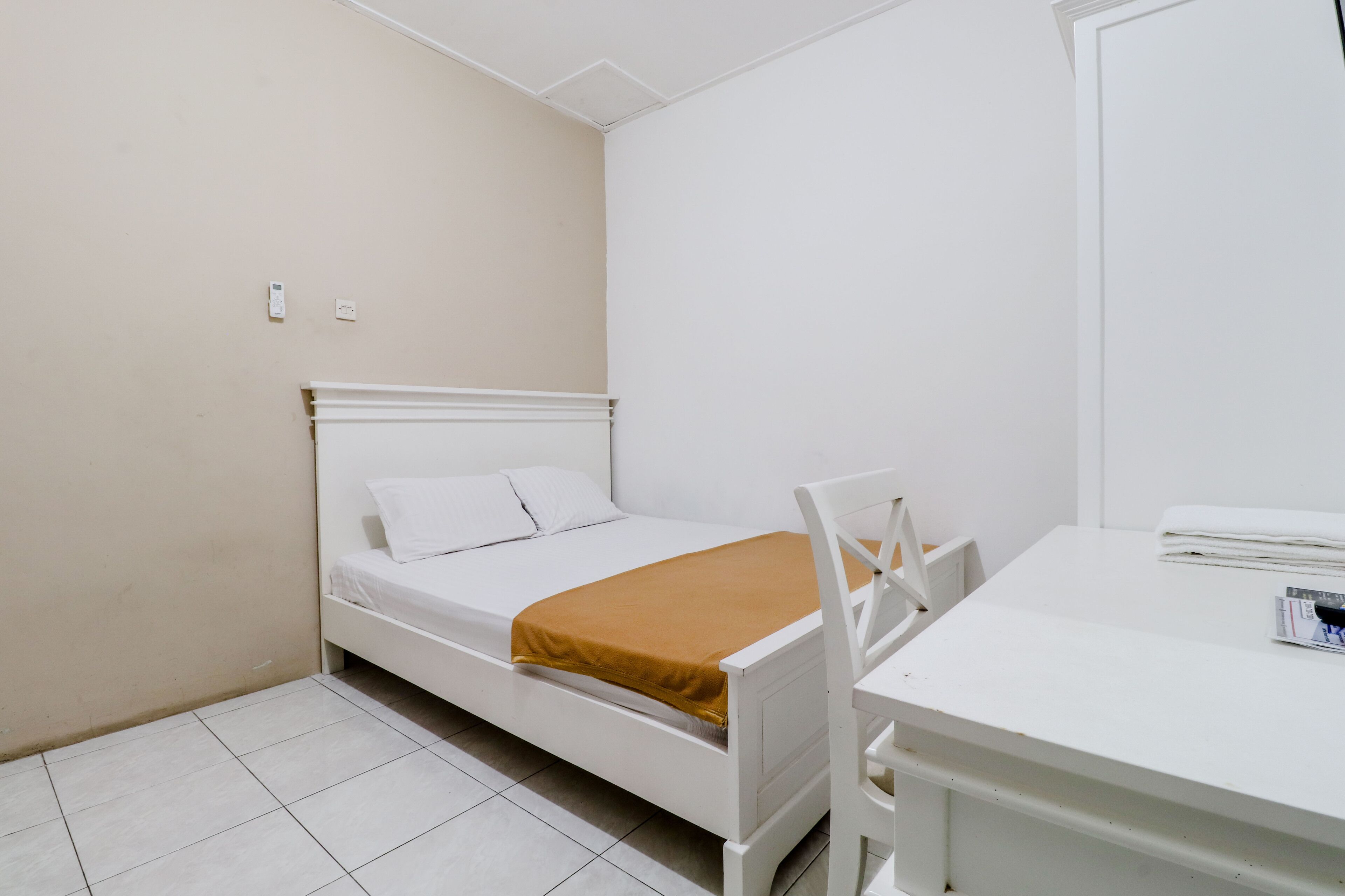 Ein kleines, sauberes Zimmer mit einem Einzelbett, einem weißen Schreibtisch und einem Stuhl.