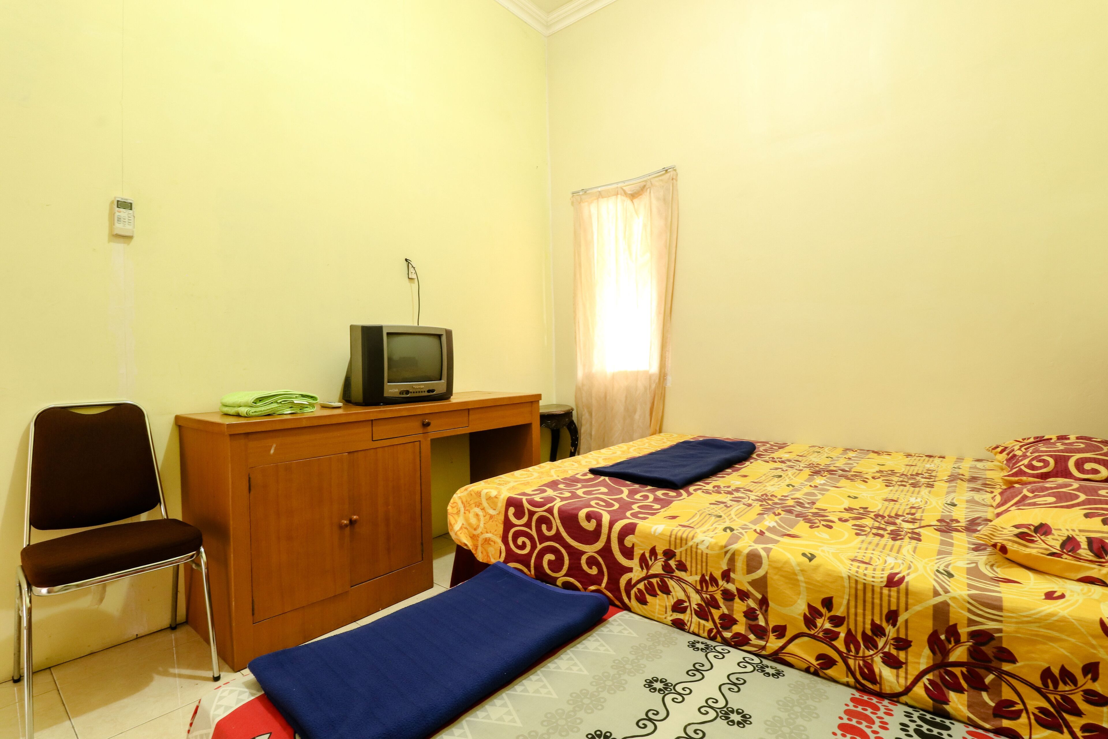 A room with a bed, a desk, a chair, and a television.