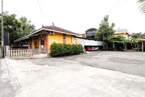 A yellow building with a tiled roof, a covered porch, and a gated entrance.