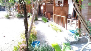 A courtyard with a wooden pergola, outdoor seating, and a variety of plants. - Penginapan Griya Watukelir (Tepus)