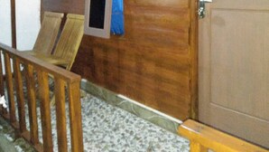 A wooden interior with a door, a window with a curtain, and a wooden railing. - Penginapan Griya Watukelir (Tepus)