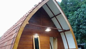 A small, wooden, A-frame structure with a porch and potted plants. - Penginapan Griya Watukelir (Tepus)