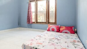 Quarto com cama, janela com cortinas e chão de azulejos.