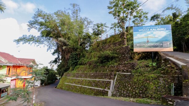 Estrada que conduz a um edifício com uma placa anunciando ecoturismo.