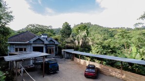 Uma casa rústica com telhado de cerâmica, varanda coberta e entrada de terra.