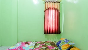 A small room with a single bed, a window with curtains, and a green wall. - Serut 2 Homestay - Hostel (Kulon Progo)