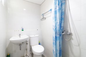 A bathroom with a white sink, toilet, and shower. - Apartment Gunawangsa Merr by Rava (Surabaya)