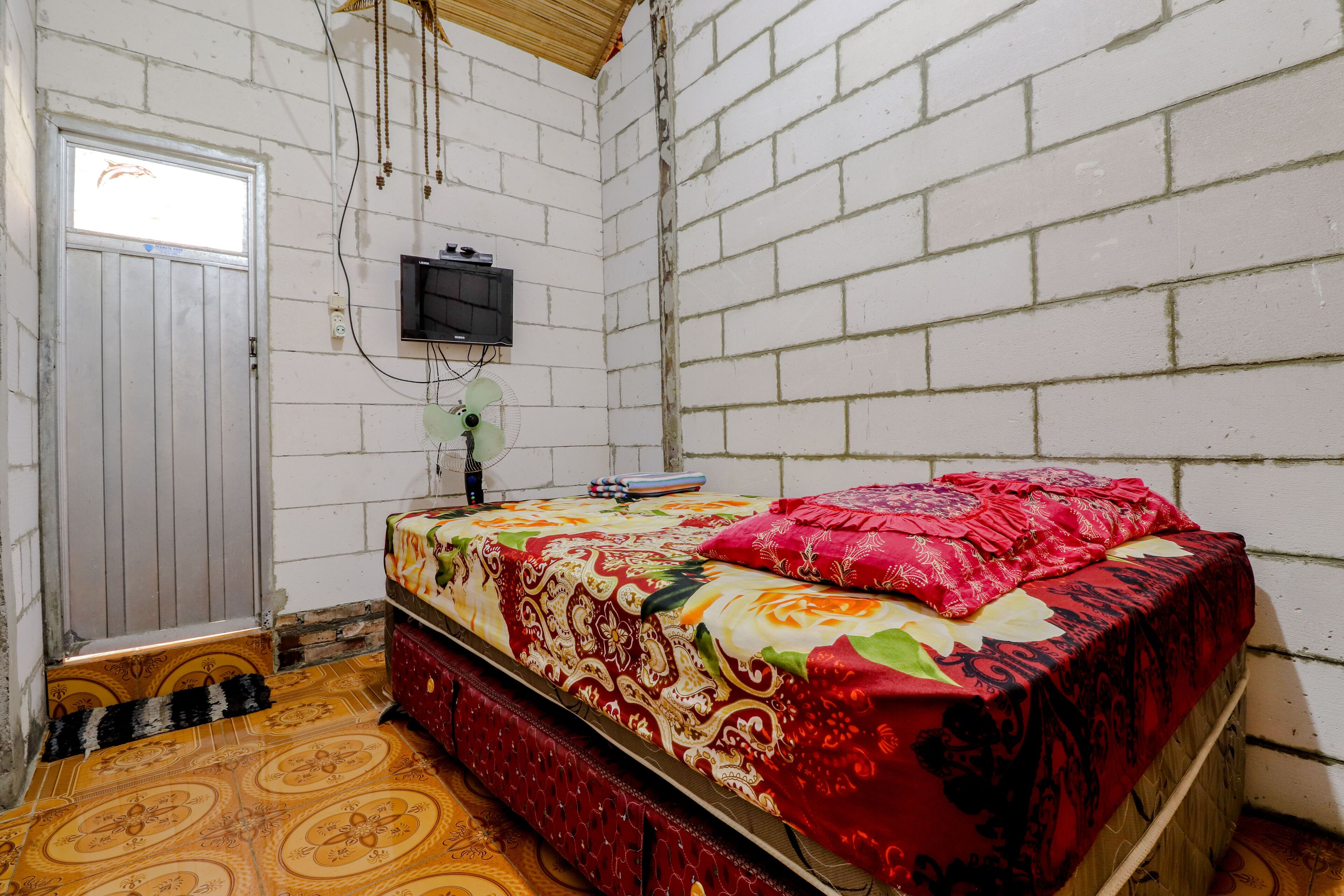 A room with a bed, a television mounted on the wall, and a door.