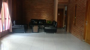 Un'ampia hall con parete in mattoni, pavimento piastrellato e angolo salotto con divani in pelle e tavolino da caffè.