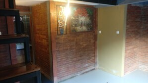 Una stanza con pareti in mattoni, uno scaffale in legno e una porta.