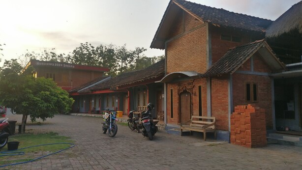 Un edificio tradizionale in mattoni con tetto in tegole, un portico coperto e una piccola panca di legno.