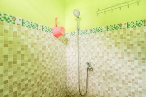 Un baño con ducha, grifo y estante en la pared.