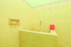 A bathroom with yellow tiles, a shower, a soap dish, and a red towel. - Penginapan Roro Mendut Syariah by Zuzu (Mungkid)