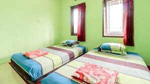 Una habitación con dos camas, paredes verdes y una ventana con cortinas rojas.