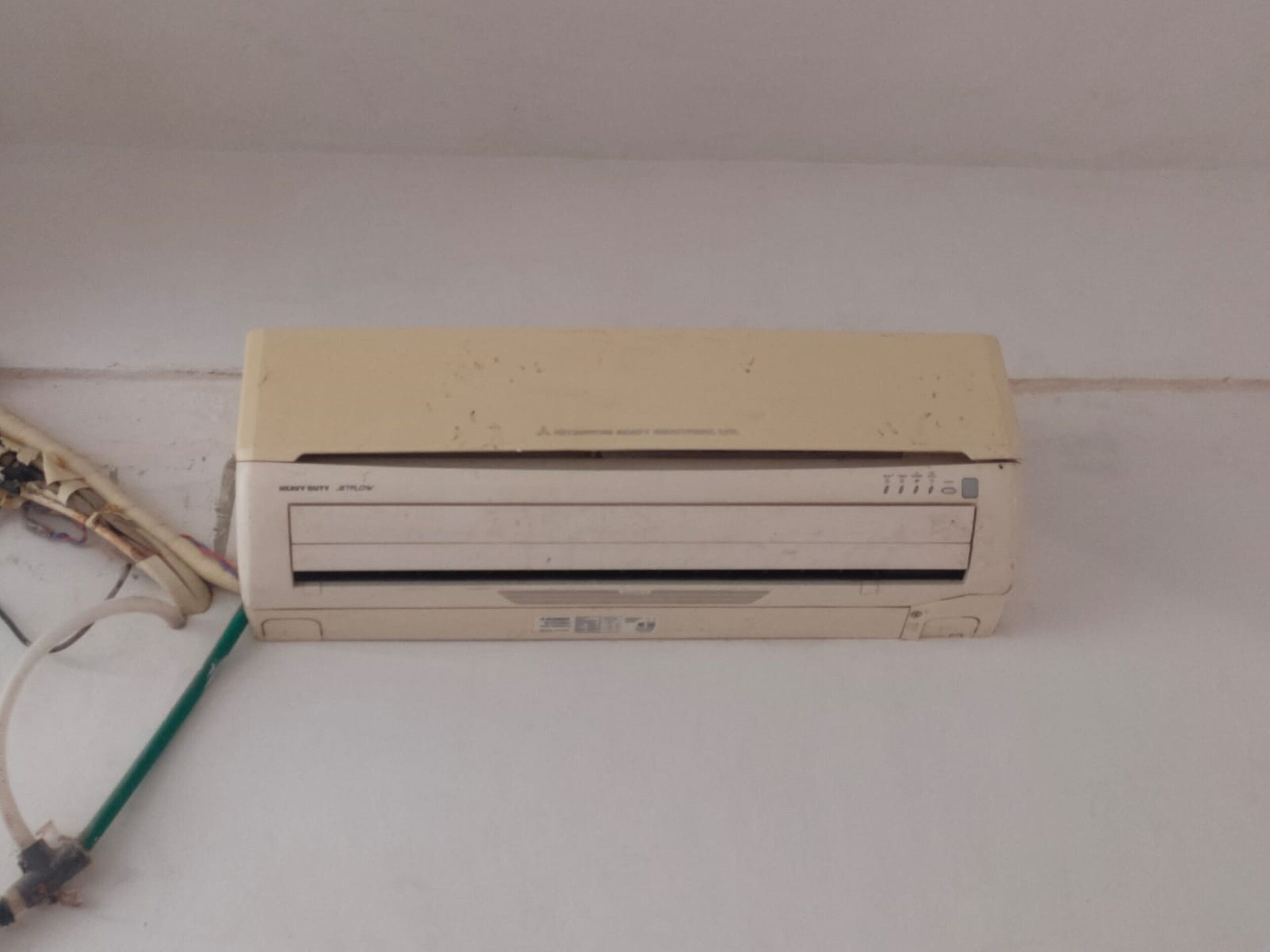 Una impresora color beige con un cable verde conectado, sobre una superficie blanca.