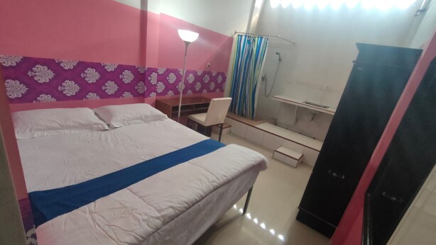 A bedroom with a bed, a desk, a chair, a wardrobe, and a shower area. - Charisma Residence Syariah (Surabaya)