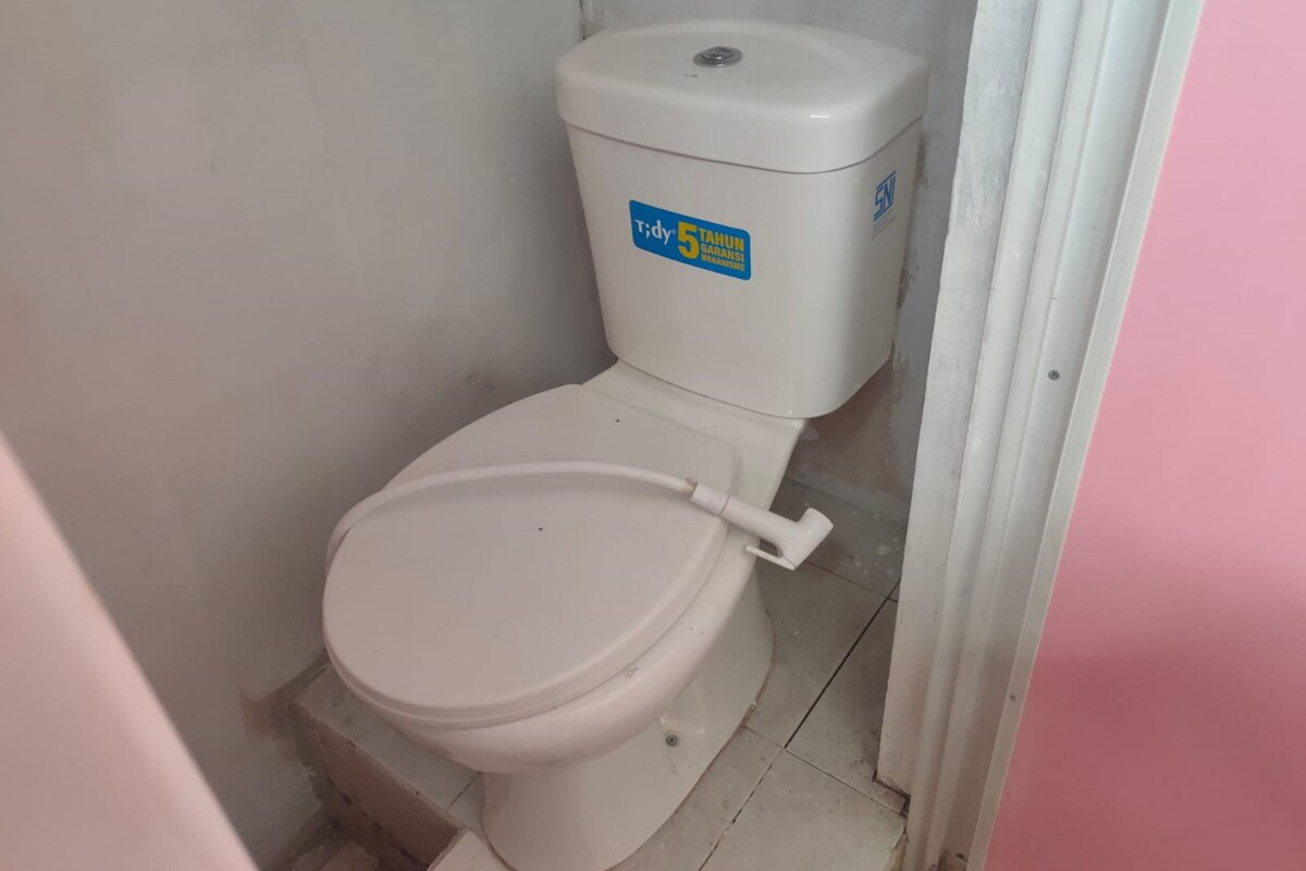 A small, white toilet with a blue sticker on the tank.