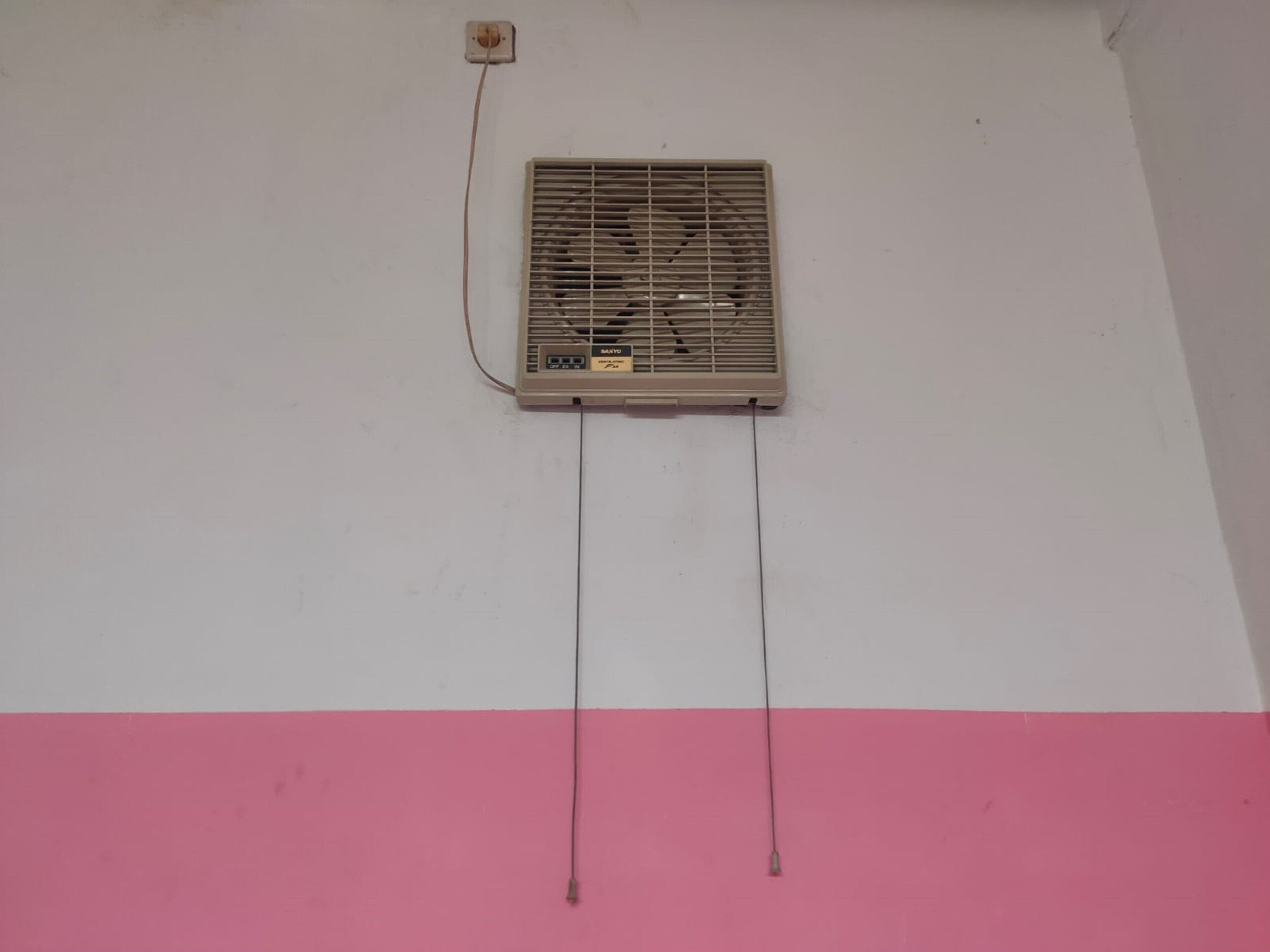 Un appareil de climatisation fixé au mur, doté d’un panneau de commande et de deux câbles qui en partent.