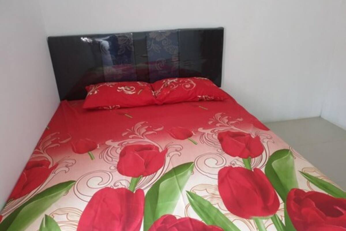 Un lit avec une couvre-lit à motifs floraux rouges et des coussins assortis.