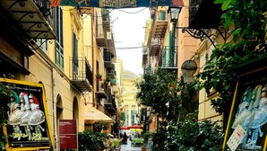 A narrow cobblestone street with buildings on either side, outdoor seating areas, and posters advertising events. - Sicilian Rooms Palermo (Palermo)