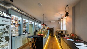 Zona de bar con mostrador, taburetes y estantes llenos de botellas.