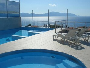 A pool area with a view of the sea and mountains.