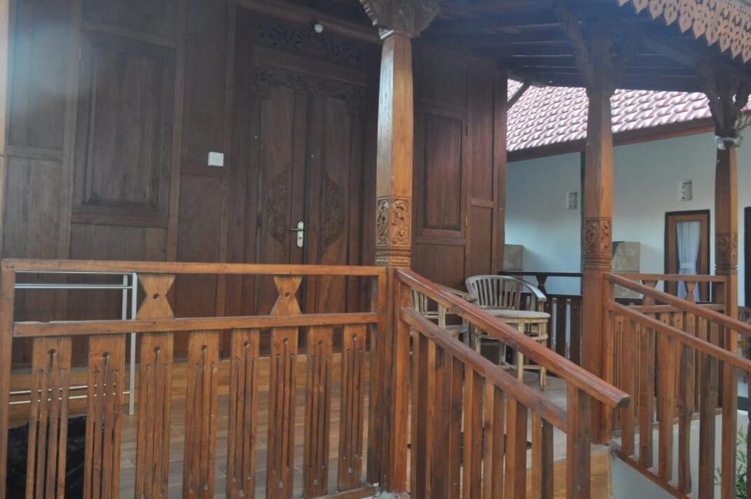 A wooden staircase with intricate carvings leading to a covered area with a tiled roof.