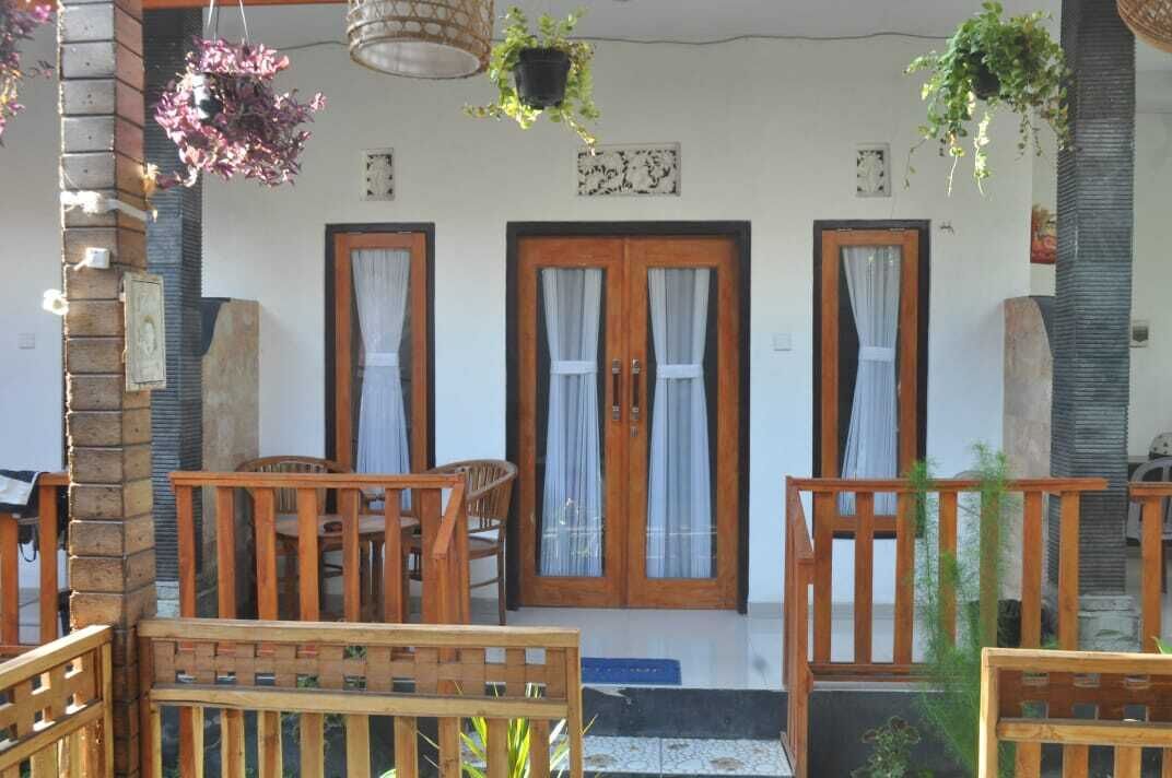 A wooden porch with two doors, a brick wall, and hanging plants.