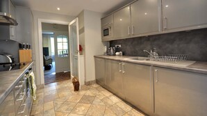 A modern kitchen with grey cabinets, a stainless steel stove, and a tiled floor. - Verdant (Poole)