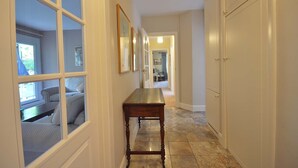 A hallway with a wooden bench, a door, and a window with a view of a room. - Verdant (Poole)