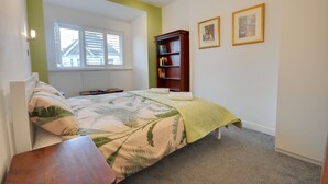 Ein Schlafzimmer mit einem Bett, einem Nachttisch, einem Bücherregal und einem Fenster mit Jalousien.