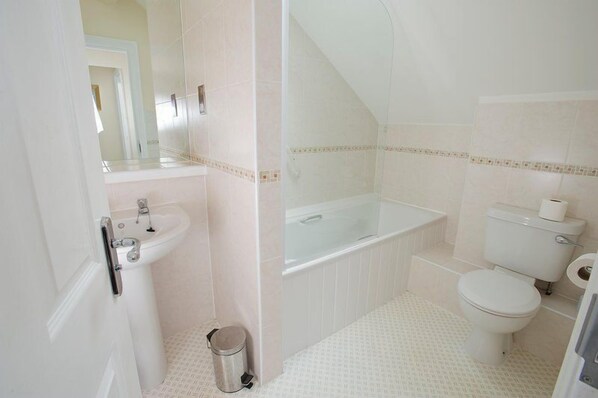 A bathroom with a sink, toilet, bathtub, and a trash can.