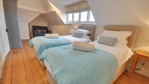 Quarto com duas camas, um guarda-roupa de madeira e uma janela com vista.