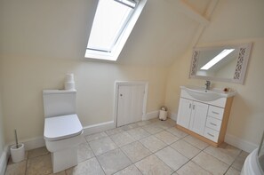 A bathroom with a skylight, toilet, sink, and cabinet. - Studland Retreat (Bournemouth)