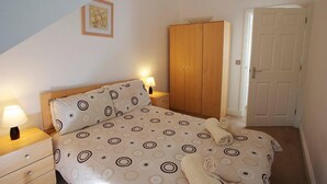 Une chambre à coucher avec un lit, des tables de chevet, une armoire et une porte.
