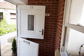Classic entrance with a touch of greenery, featuring a door with a modern handle and a window.