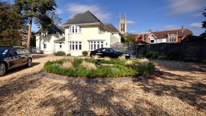 A house with a driveway, a garden, and a church in the background. - Somerville Coach House 2 (Bournemouth)