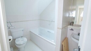 A bathroom with a toilet, bathtub, and sink. - Shell Cottage (Bournemouth)
