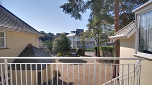 A residential area with a balcony, a parked car, and houses in the background. - Somerville Coach House 4 (Bournemouth)