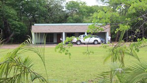 A building with a brick facade, surrounded by a grassy area and trees. - Waterfalls Apartments (Lusaka)
