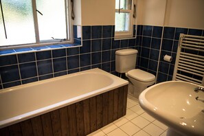 Un baño con una bañera de madera, un inodoro blanco y un lavamanos blanco.