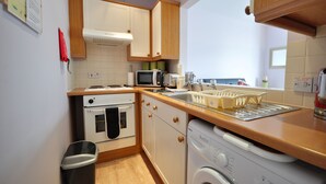 Una cocina compacta con microondas, tostadora, lavabo y lavadora.