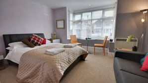 Un dormitorio moderno con una cama grande, un escritorio y una silla.