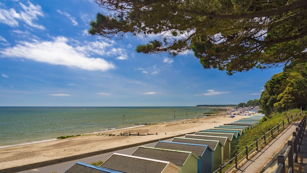 Une rangée de cabanes de plage situées en bord de mer, offrant une vue sur la mer et la plage.