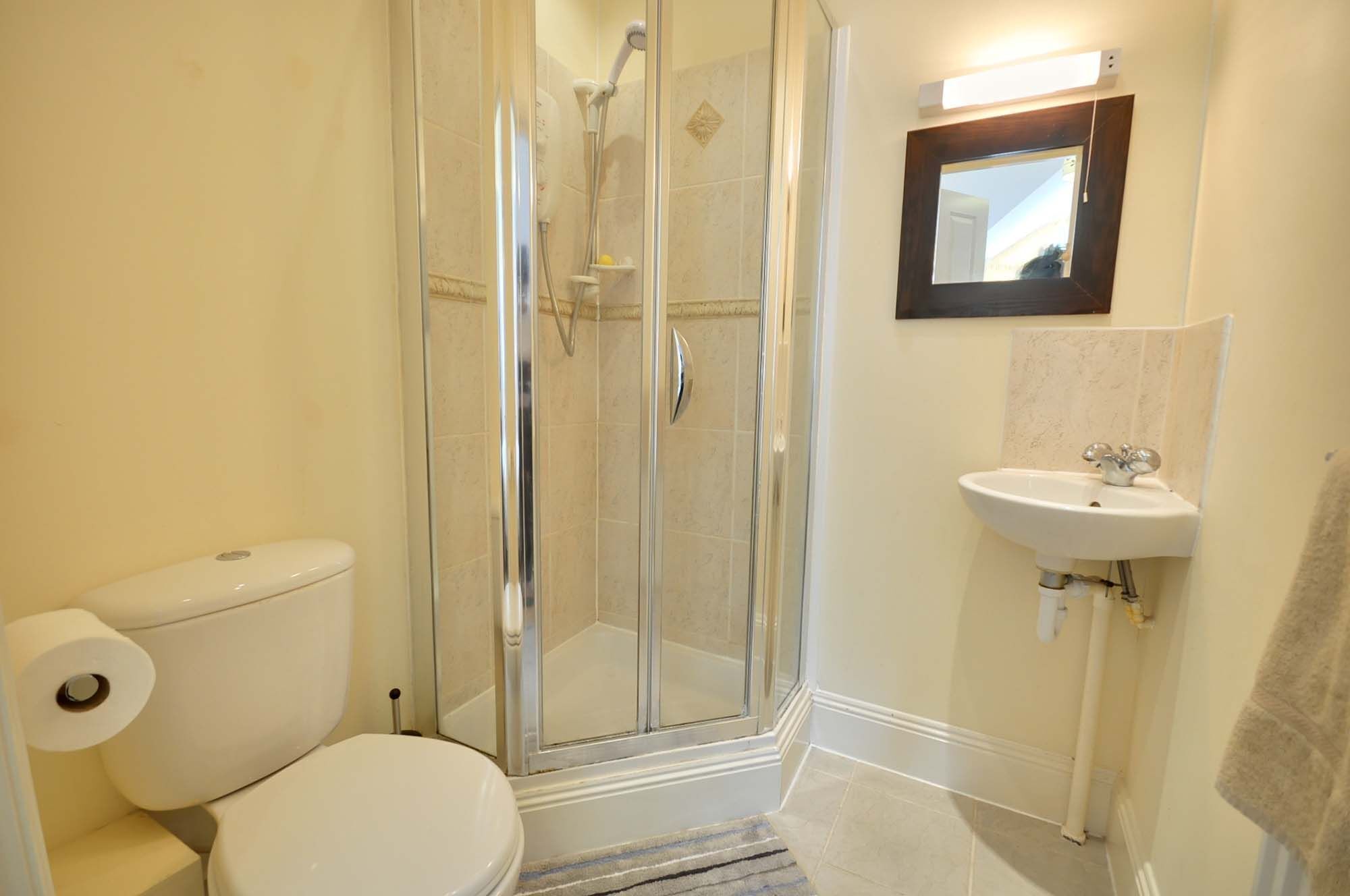 A bathroom with a toilet, a glass-enclosed shower, and a sink.