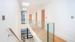 A modern interior with a glass railing, wooden flooring, and recessed lighting. - Spyglass (Poole)