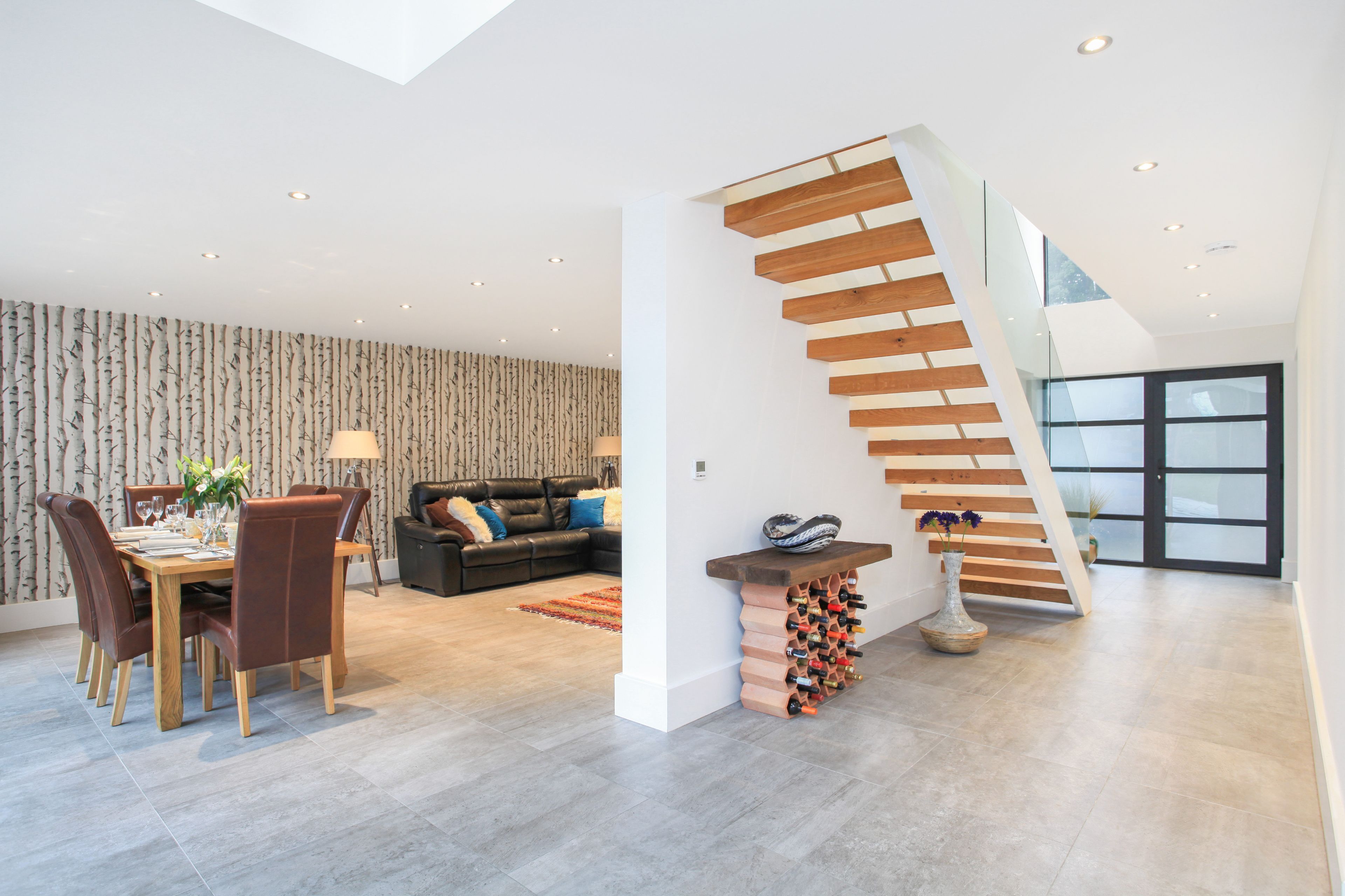 A modern living space with a dining area, a staircase, and a wine rack.