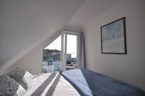 Una camera da letto con un letto, una grande finestra e un quadro appeso al muro.
