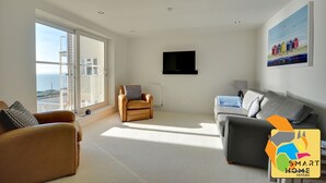 Un salón amplio con un ventanal grande, un sofá, una silla y un televisor.
