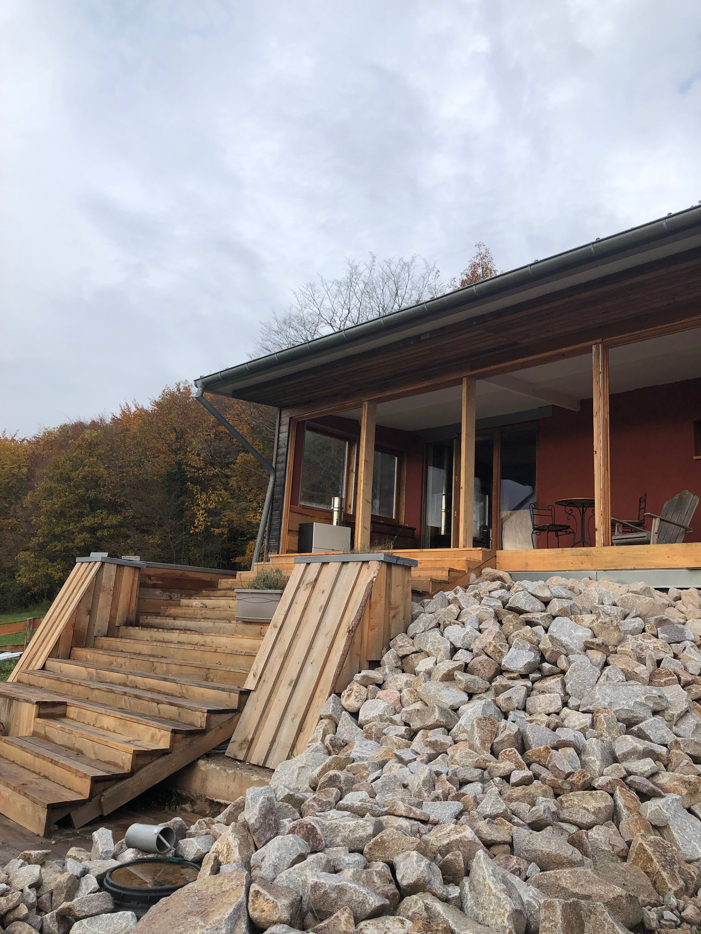 Una casa moderna con una escalera de madera que lleva a un porche cubierto.
